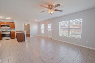 Kitchen with appliances with stainless steel finishes, light tile patterned floors, open floor plan, and ceiling fan