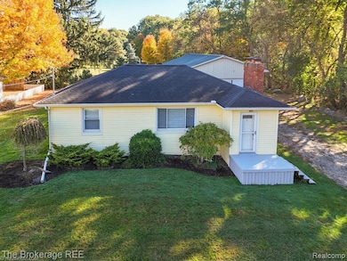 Back of property with a lawn, a chimney, and roof with shingles