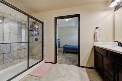 Full bath featuring ensuite bathroom, tiled shower, vanity, and baseboards