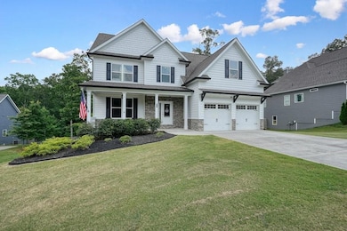 Craftsman house featuring an attached garage, concrete driveway, stone siding, and a front lawn