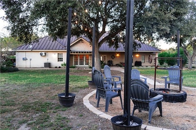Back of property with a patio area, a metal roof, a lawn, and an outdoor fire pit
