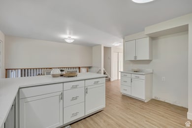 Kitchen with light countertops, light wood-style flooring, and white cabinets