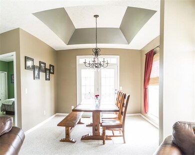 Large sunny dining room with tray ceiling and door