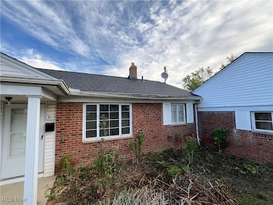 View of home's exterior featuring a shingled roof, brick siding, and a chimney