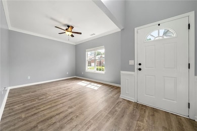 Entrance foyer featuring a ceiling fan, wood finished floors, ornamental molding, and baseboards