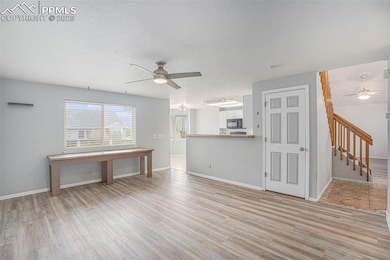 Unfurnished living room featuring ceiling fan, light wood-style flooring, and baseboards