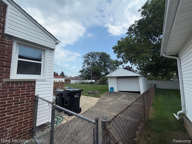 Fenced backyard featuring an outbuilding, a garage, a gate, a patio, and driveway