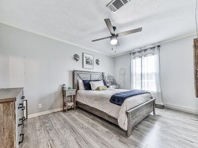 Bathroom with a shower stall, a textured ceiling, ornamental molding, and wood finished floors