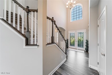 Foyer entrance with stairs, french doors, a chandelier, a towering ceiling, and wood finished floors