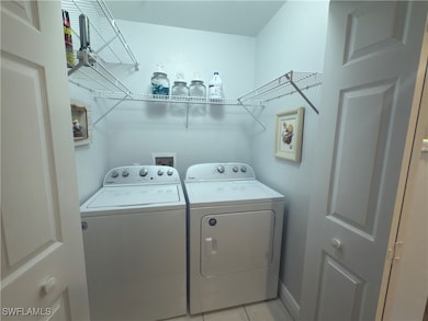 Laundry area featuring laundry area, light tile patterned flooring, and washing machine and clothes dryer