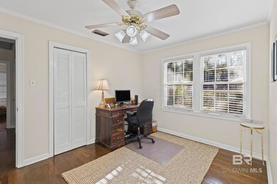 Office area featuring ornamental molding, dark wood-style flooring, and ceiling fan