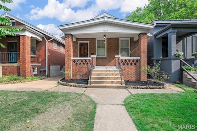 Bungalow-style home with covered porch, brick siding, and a front yard