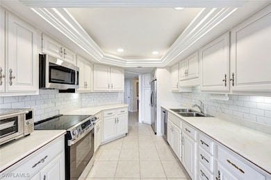 Kitchen with appliances with stainless steel finishes, white cabinets, light countertops, recessed lighting, and ornamental molding
