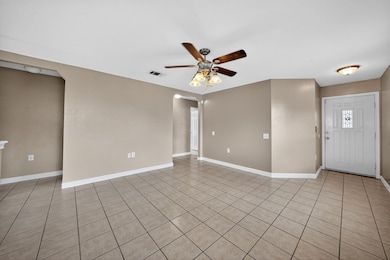 Empty room featuring light tile patterned floors, arched walkways, and ceiling fan