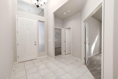 Foyer with light tile patterned flooring and a chandelier