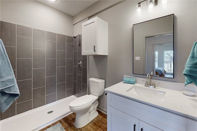 Bathroom featuring toilet, a tile shower, wood fin