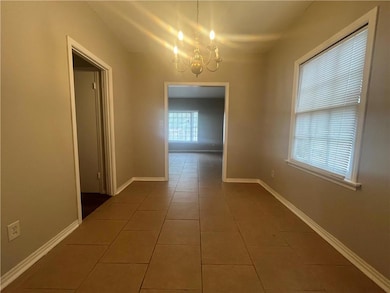 Hall featuring a chandelier, tile patterned flooring, and baseboards