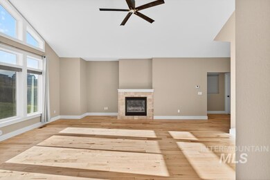 Unfurnished living room with a tiled fireplace, light wood-type flooring, a ceiling fan, and vaulted ceiling