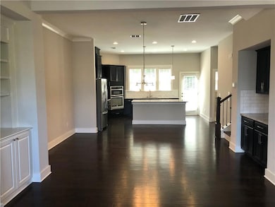 Kitchen with stainless steel refrigerator, dark wood-style floors, tasteful backsplash, a center island, and dark cabinetry