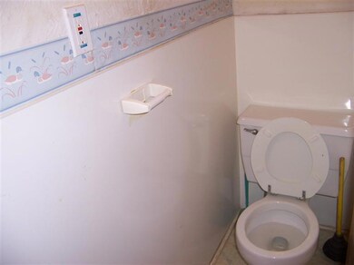 Bathroom off the kitchen near stairs leading to basement.