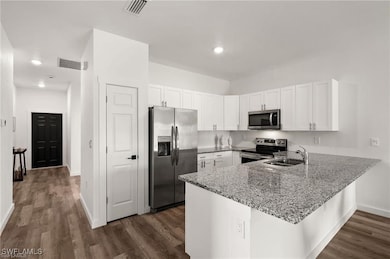 Kitchen featuring white cabinetry, kitchen peninsula, and stainless steel appliances