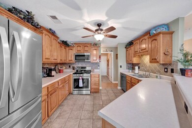 Kitchen with stainless steel appliances, tasteful backsplash, a sink, light tile patterned flooring, and a ceiling fan