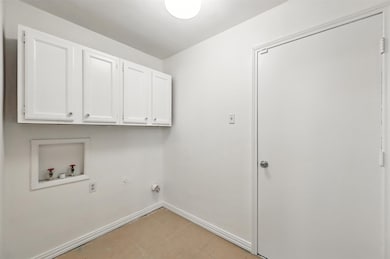Washroom with cabinet space, washer hookup, and light tile patterned floors