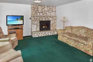 Carpeted living room featuring a fireplace and a textured ceiling