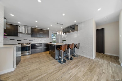 Kitchen featuring a kitchen bar, modern cabinets, stainless steel range oven, decorative light fixtures, and recessed lighting