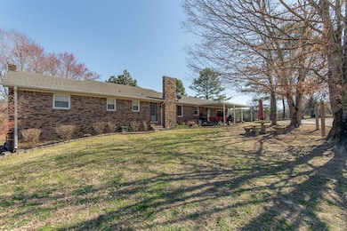 Rear view of house featuring a lawn and a chimney