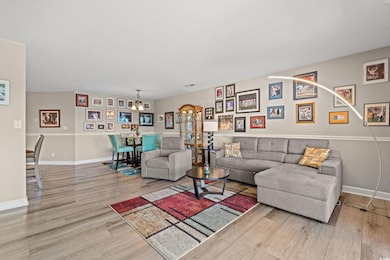 Living room with light hardwood / wood-style floors and an inviting chandelier