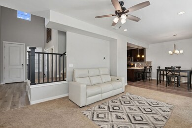 Living area with light colored carpet, a ceiling fan, recessed lighting, a chandelier, and light wood-type flooring
