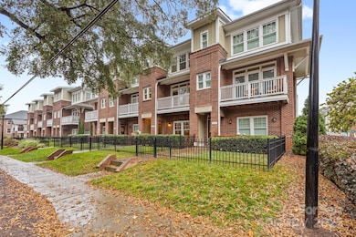 Attractive townhome exterior with classic brick design, upper-level balconies, and a fenced front lawn offering charm and functionality.