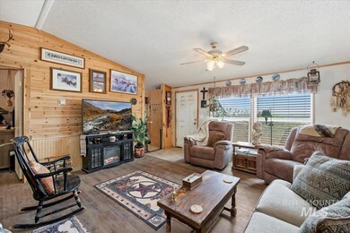 Living area featuring wooden walls, lofted ceiling, a glass covered fireplace, ceiling fan, and a textured ceiling