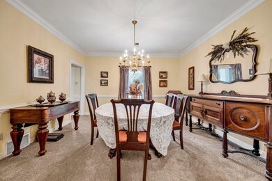 Dining room with a chandelier, light carpet, and crown molding