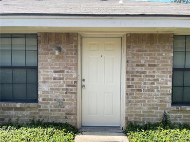 View of exterior entry with brick siding and a shingled roof