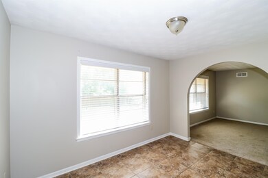 Empty room with arched walkways and light tile patterned floors