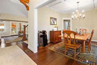 Dining room featuring a chandelier, dark wood-type flooring, stairs, coffered ceiling, and beamed ceiling