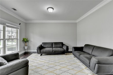 Living area with crown molding, baseboards, and wood finished floors