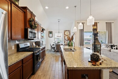 The kitchen features a stainless steel undermount sink, gas range, upgraded pendant lighting, and subway style backsplash.