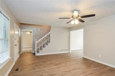 Spare room with ceiling fan, stairs, light wood-type flooring, baseboards, and healthy amount of natural light
