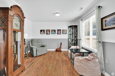 Living area with wood finished floors and crown molding