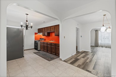 Kitchen featuring hanging light fixtures, freestanding refrigerator, light countertops, gas stove, and a chandelier
