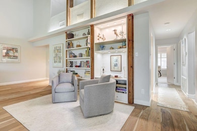 Sitting room with light wood-style floors and a towering ceiling