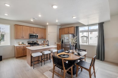 Kitchen with an island with sink, stainless steel appliances, light countertops, a kitchen breakfast bar, and light wood-style flooring
