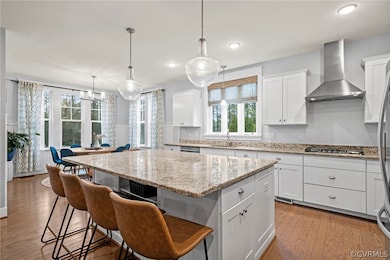Kitchen with wall chimney range hood, light hardwo