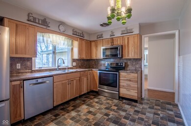 kitchen with tasteful backsplash, dark countertops, light brown cabinets, appliances with stainless steel finishes, and a sink