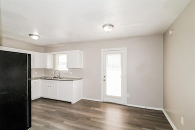 Kitchen featuring freestanding refrigerator, white cabinetry, dark wood-style floors, and light countertops