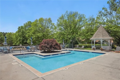 Community pool featuring a gazebo, a patio, and view of wooded area