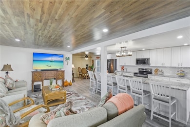 Living room with a ceiling fan, wood finished floors, wooden ceiling, and recessed lighting